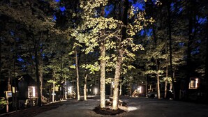 A campground with tents and a central tree illuminated by lights. - Scandinavian Treetop Bliss @ Terralodge (Monteagle)