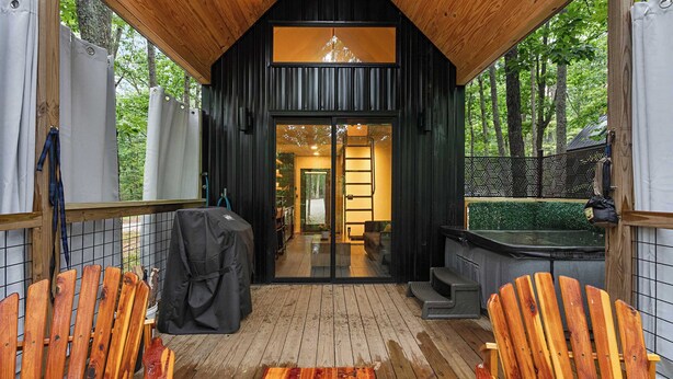 A wooden cabin with a glass door entrance, a covered porch, and a hot tub. - Scandinavian Treetop Bliss @ Terralodge (Monteagle)