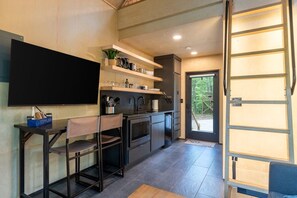 Una cucina moderna con una TV a schermo piatto, sgabelli da bar e scaffali a incasso.