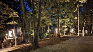 A row of wooden cabins in a forest, connected by a dirt path. - Scandinavian Treetop Bliss @ Terralodge (Monteagle)