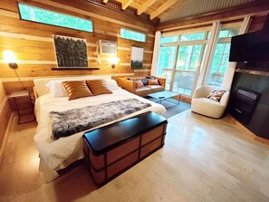 Una camera da letto moderna con un letto grande, una poltrona, una televisione e un camino.