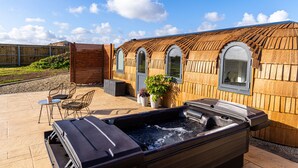 Et spaområde med jacuzzi, trævægge, hvælvede vinduer og udendørs siddepladser.