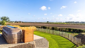 A rural landscape with a wooden structure, a well-maintained lawn, and fields in the background. - Indrek - Mayflower Meadow (Driffield)