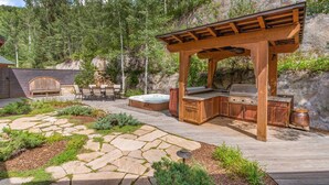 Un área de cocina al aire libre con una parrilla, asientos y un jacuzzi.