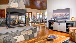 Una sala de estar acogedora con chimenea de piedra, suelo de madera, televisor y sofá de cuero.