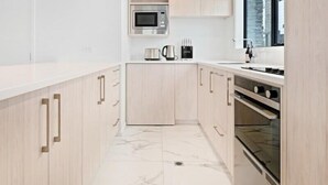 A modern kitchen with light wood cabinetry, a built-in microwave, and a stove. - Central Convenience on Armagh (Christchurch)
