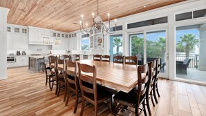 Cozinha espaçosa com armários brancos, uma grande mesa de jantar de madeira e um lustre.