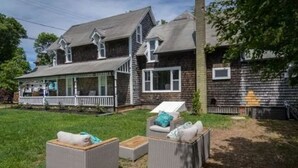 A two-story house with a porch, outdoor seating area, and a visible garage.