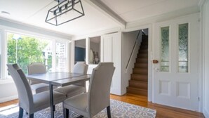 A dining area with a table and chairs, a staircase, and a door with frosted glass panels.