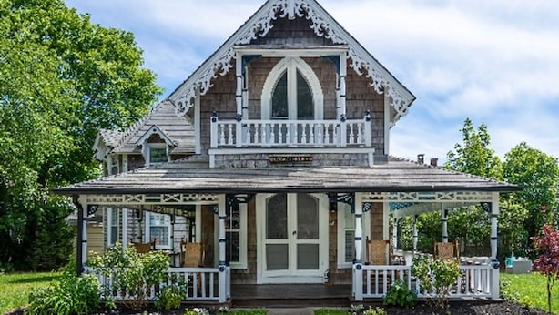 A Victorian-style house with a central entrance, a balcony, and a porch with railings.