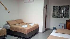 A bedroom with a bed, a bedside table, a wall-mounted air conditioner, and a wall art piece. - Pousada Oceano e Mar (Ilhabela)