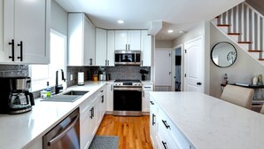 A modern kitchen with white cabinetry, stainless steel appliances, and a wooden floor. - Private Heated Pool - 1 Block from the Beach! (Tybee Island)