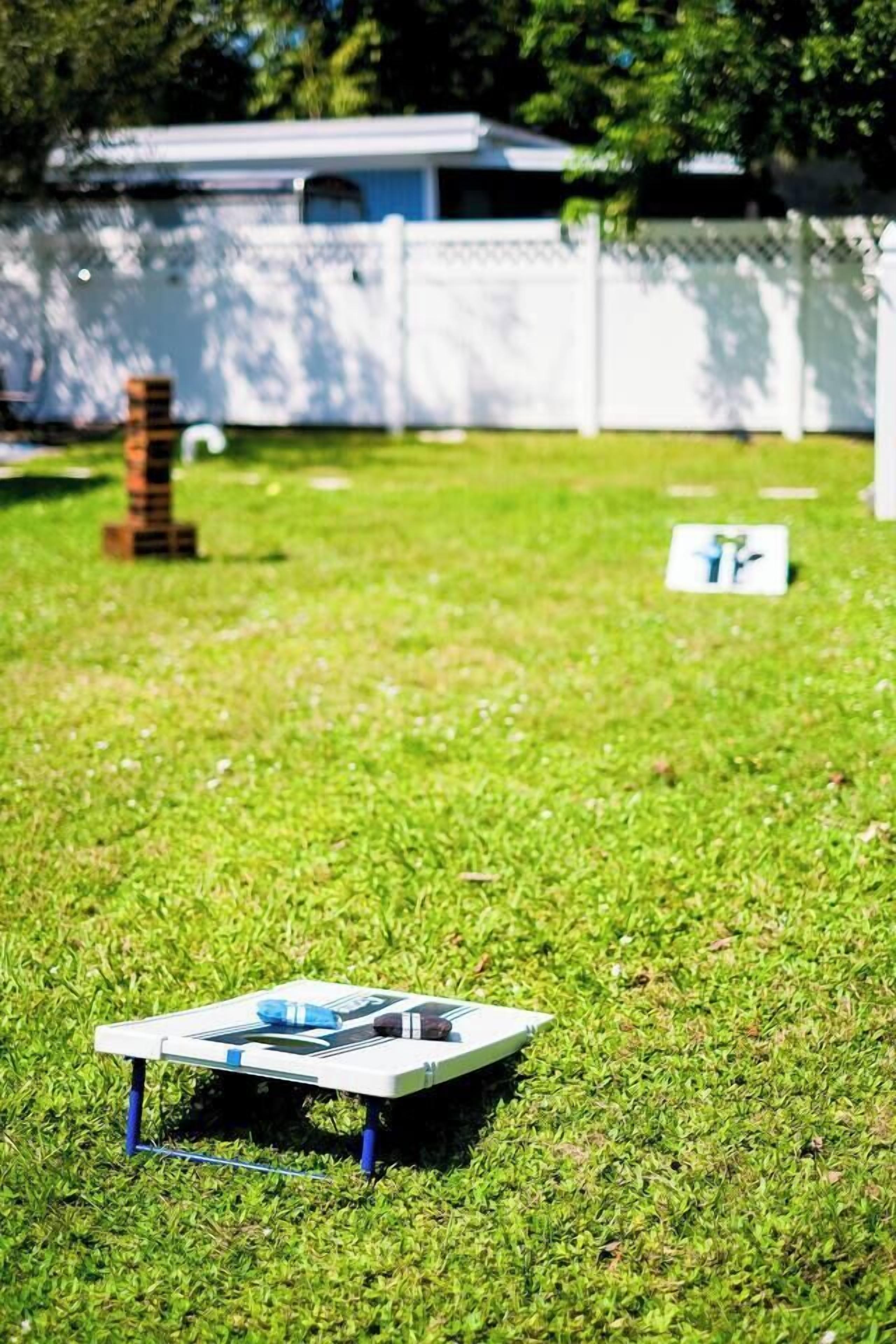 A model airplane on a grassy lawn with a white fence and a building in the background.