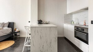 A compact kitchen with a marble island, modern appliances, and a minimalist design. - Riverview Studio in Historical Heart of Antwerp (Antwerpen)