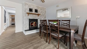 A dining area with a fireplace, wooden chairs, and a ceiling fan. - Swansea Serene | Indoor Fireplace | 5 Min to Beach (Windermere)