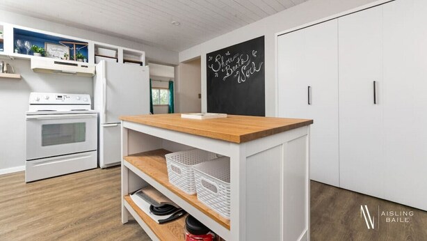 A modern kitchen with white cabinetry, a wooden countertop, and a chalkboard with writing. - Swansea Serene | Indoor Fireplace | 5 Min to Beach (Windermere)