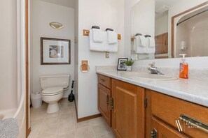 A bathroom with a toilet, sink, and wooden cabinets.