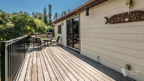 A wooden deck with outdoor seating, a sliding glass door, and a sign reading "1745 VAN SEA". - Swansea Serene | Indoor Fireplace | 5 Min to Beach (Windermere)