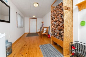A hallway with wooden flooring, a wooden bench, a wall-mounted rack, and a door.