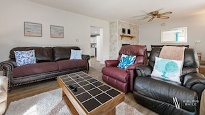 A living room with a brown leather sofa, a red leather armchair, and a wooden coffee table. - Swansea Serene | Indoor Fireplace | 5 Min to Beach (Windermere)