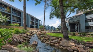 A residential area with a small stream, modern buildings, and a well-maintained garden. - Lake Conroe Retreat – Relaxing Lake Views - Fish & Swim - Ground Floor (Montgomery)