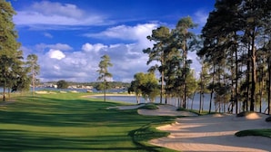 A golf course with sand bunkers, trees, and a body of water in the background. - Lake Conroe Retreat – Relaxing Lake Views - Fish & Swim - Ground Floor (Montgomery)