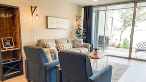 A modern living room with a sofa set, a coffee table, and a bookshelf. - Lake Conroe Retreat – Relaxing Lake Views - Fish & Swim - Ground Floor (Montgomery)