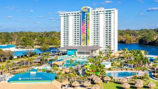 A high-rise hotel with multiple balconies overlooking a large pool area and a body of water. - Lake Conroe Retreat – Relaxing Lake Views - Fish & Swim - Ground Floor (Montgomery)