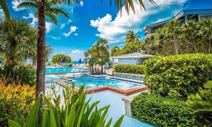 A pool area with multiple pools, surrounded by lush greenery and palm trees. - ATLANTIC HIDEAWAY- Key West (Key West)