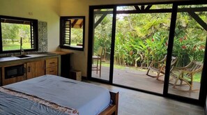 Relax in a serene space with a large bed, sliding glass door to an outdoor deck, and a wooden cabinet with a mirror.