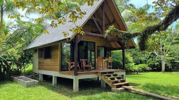 Situated in a lush environment, this cabin features a porch with stairs and comfortable seating.