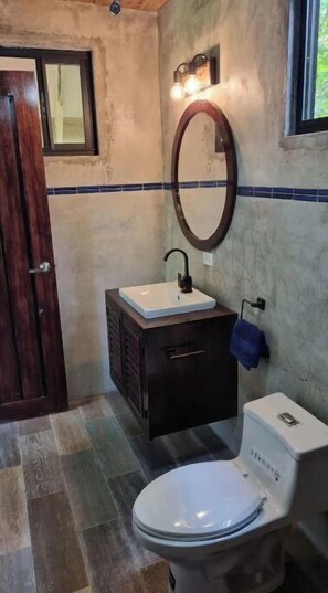 Bathroom features a toilet, sink, and mirror with a towel rack.