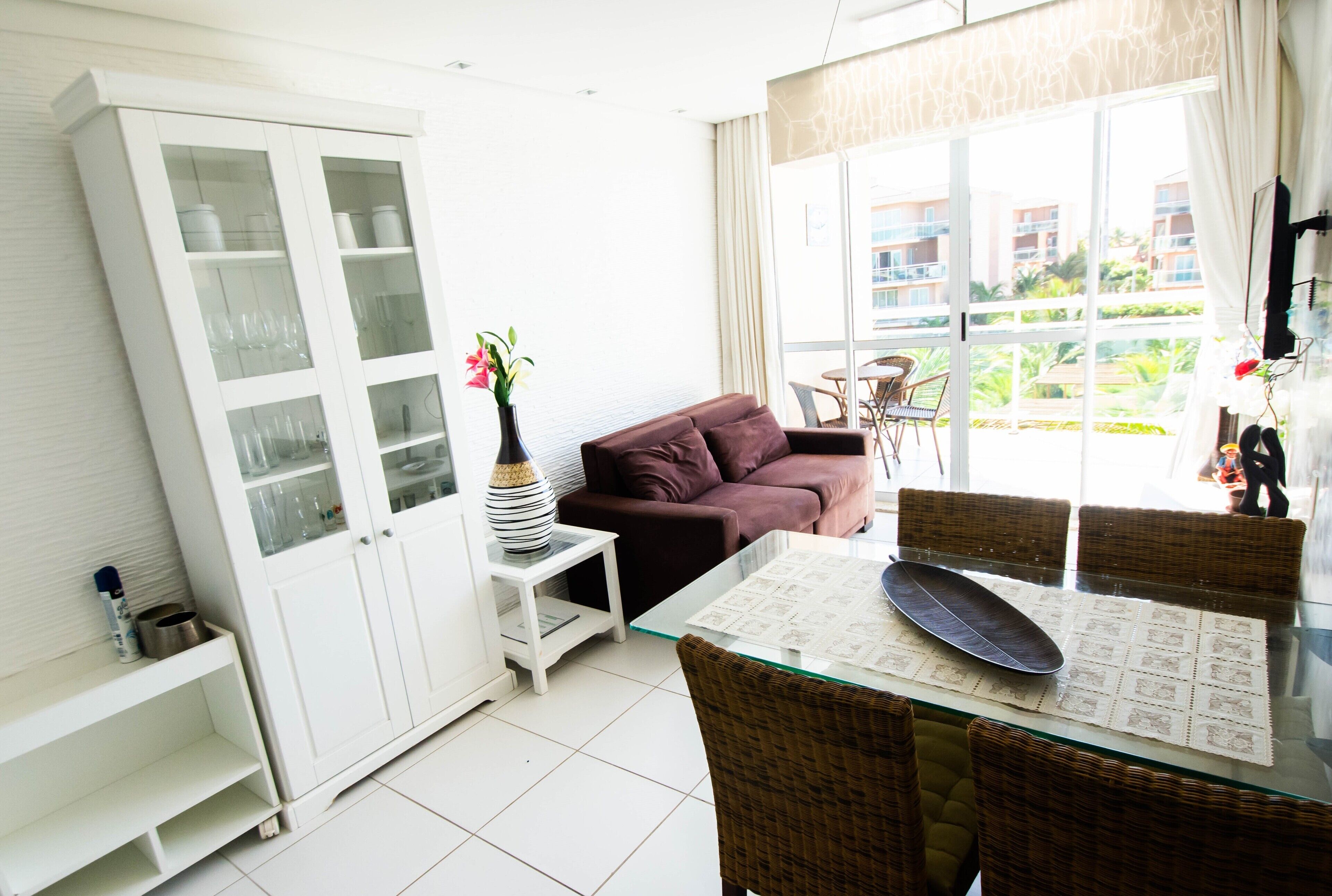 Una sala de estar moderna con una mesa de comedor de vidrio, un sofá y un mueble con puertas de cristal.