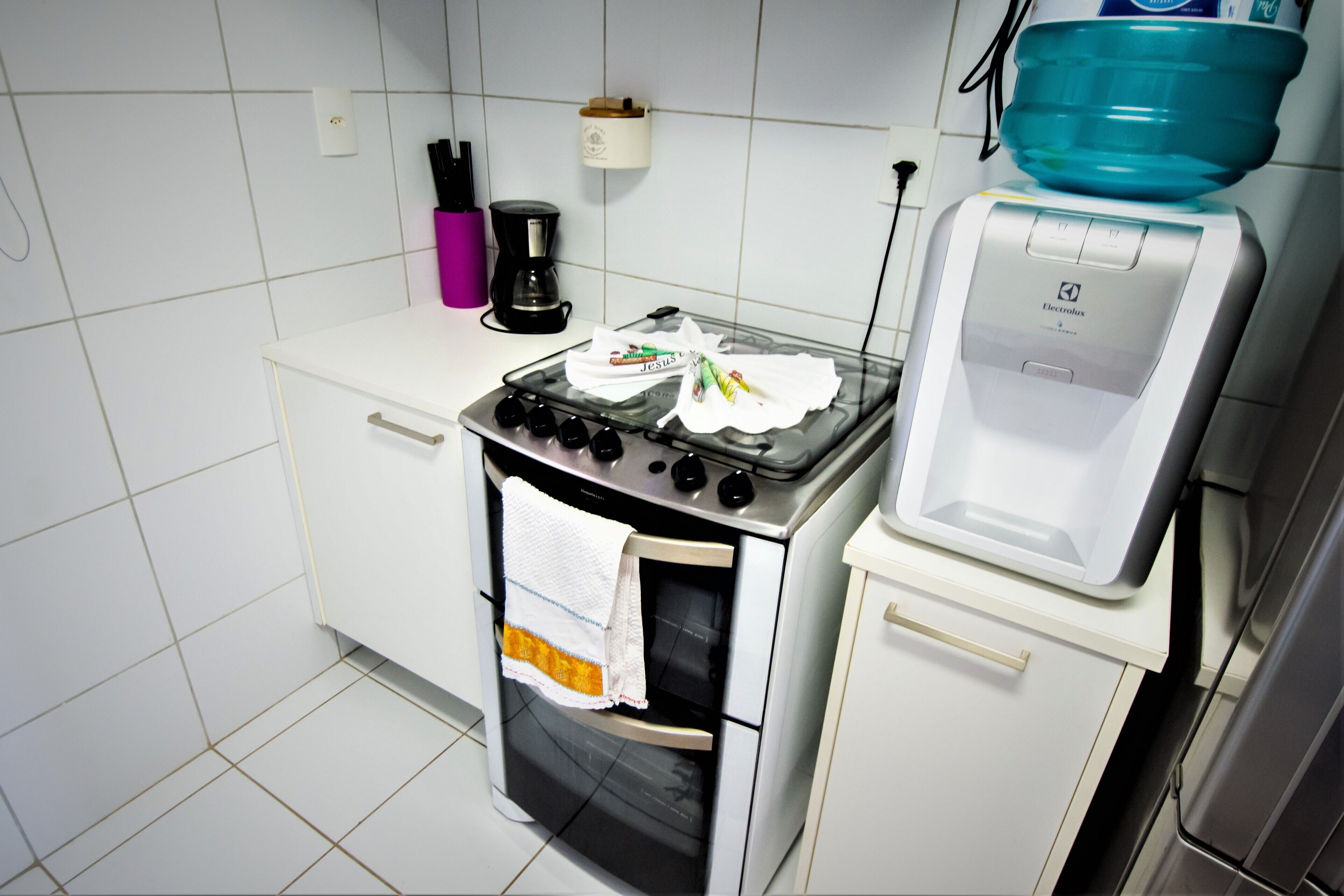 A kitchen with a stove, oven, and a water dispenser.
