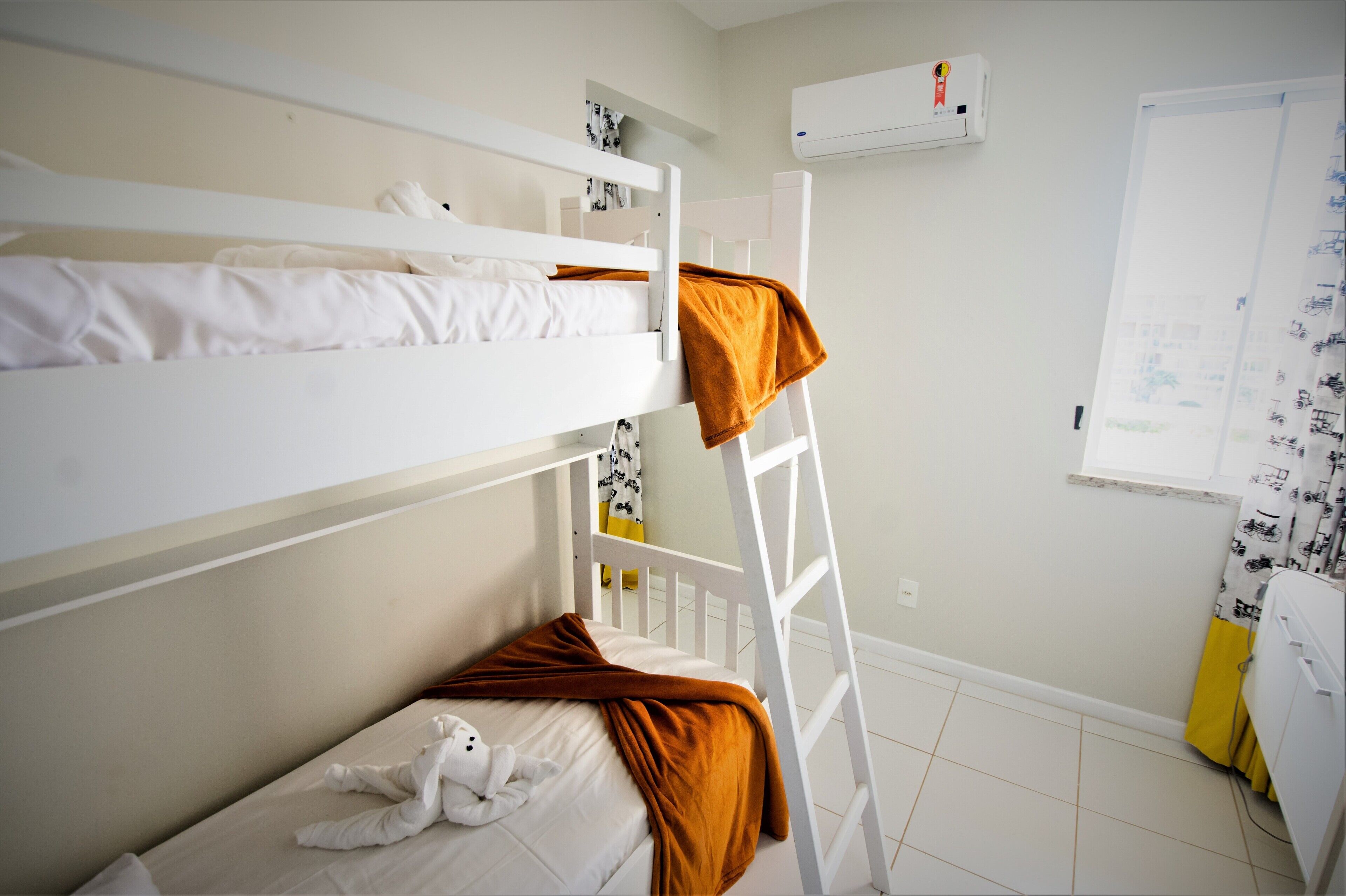 A bunk bed room with a ladder, a white air conditioner, and a whiteboard on the wall.