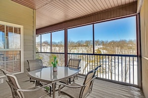A covered outdoor patio with a table and chairs, large windows, and a view of a snowy landscape. - Condo with Game Room! Walk to Pool! Close to SDC! (Branson West)