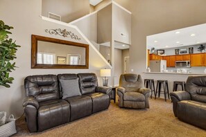 A spacious living area with a leather sofa, a recliner, and a coffee table. A staircase leads to an upper level. - Condo with Game Room! Walk to Pool! Close to SDC! (Branson West)