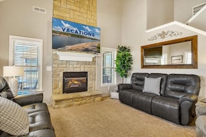 A living room with a stone fireplace, a leather sofa, and a large mirror. - Condo with Game Room! Walk to Pool! Close to SDC! (Branson West)