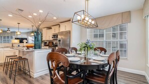 Una cocina moderna con una isla central, taburetes de bar y un comedor con una mesa redonda y sillas.