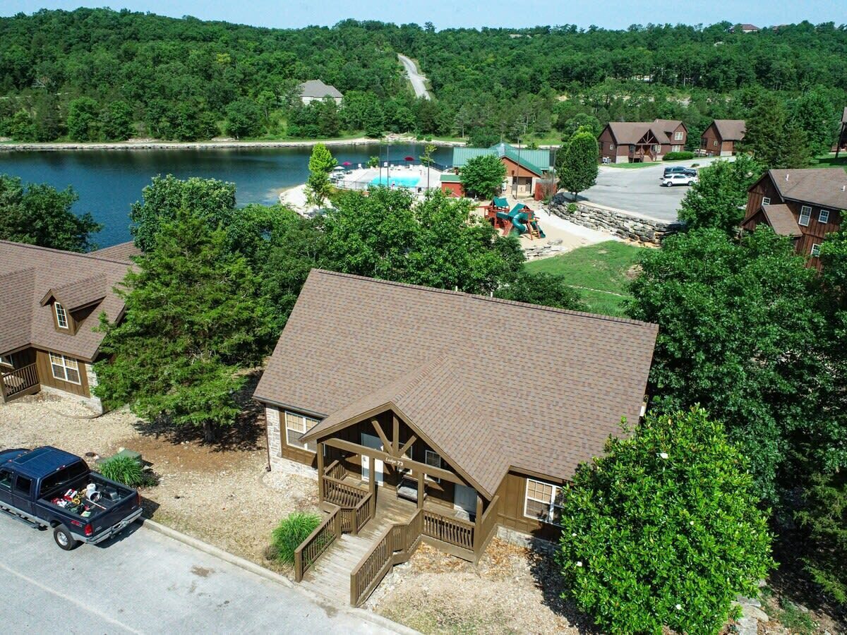 A lodge with a large deck, a swimming pool, and a view of a lake.