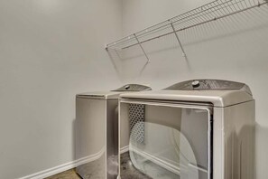 A laundry room with two stacked washing machines and a drying rack.