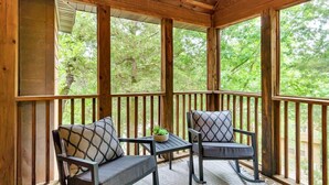 A wooden deck with two chairs and a small table, surrounded by tall wooden railings and large windows. - Modern Lodge, 3 Miles from Silver Dollar City! (Reeds Spring)
