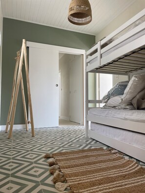 Ein Zimmer mit einem Etagenbett, einem hölzernen Staffelei und einem gemusterten Teppich.