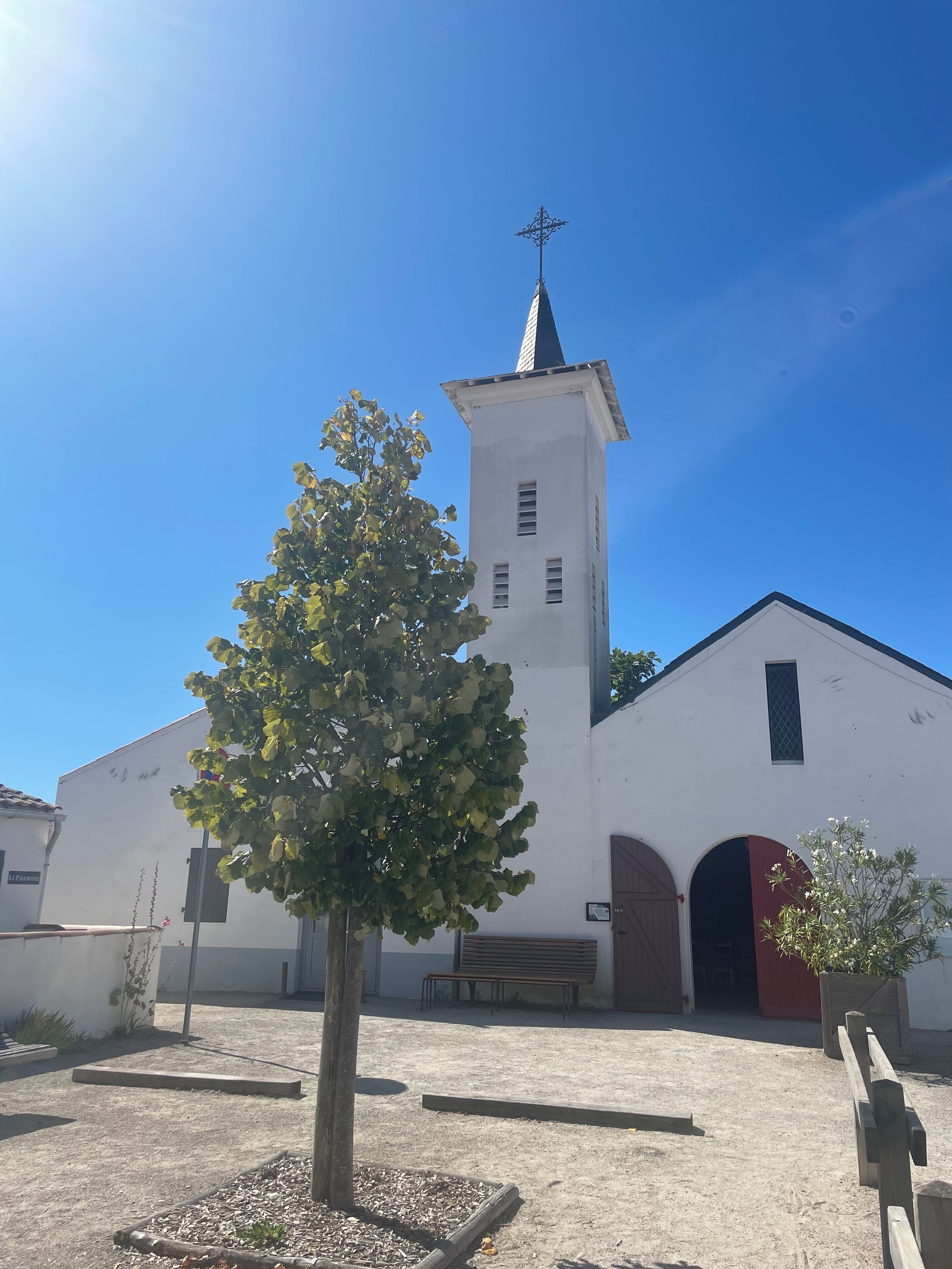 A white church with a bell tower and a cross on top.