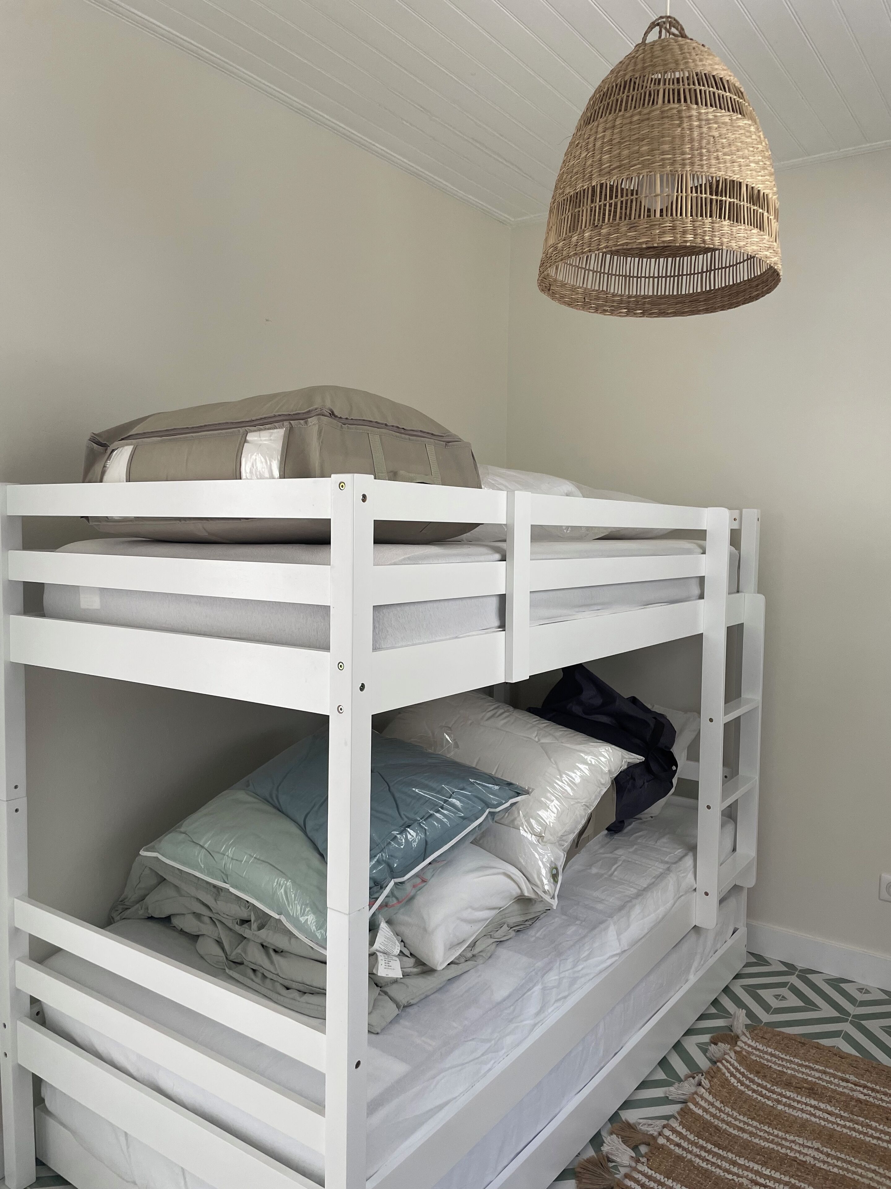 A bunk bed with a woven pendant light above.