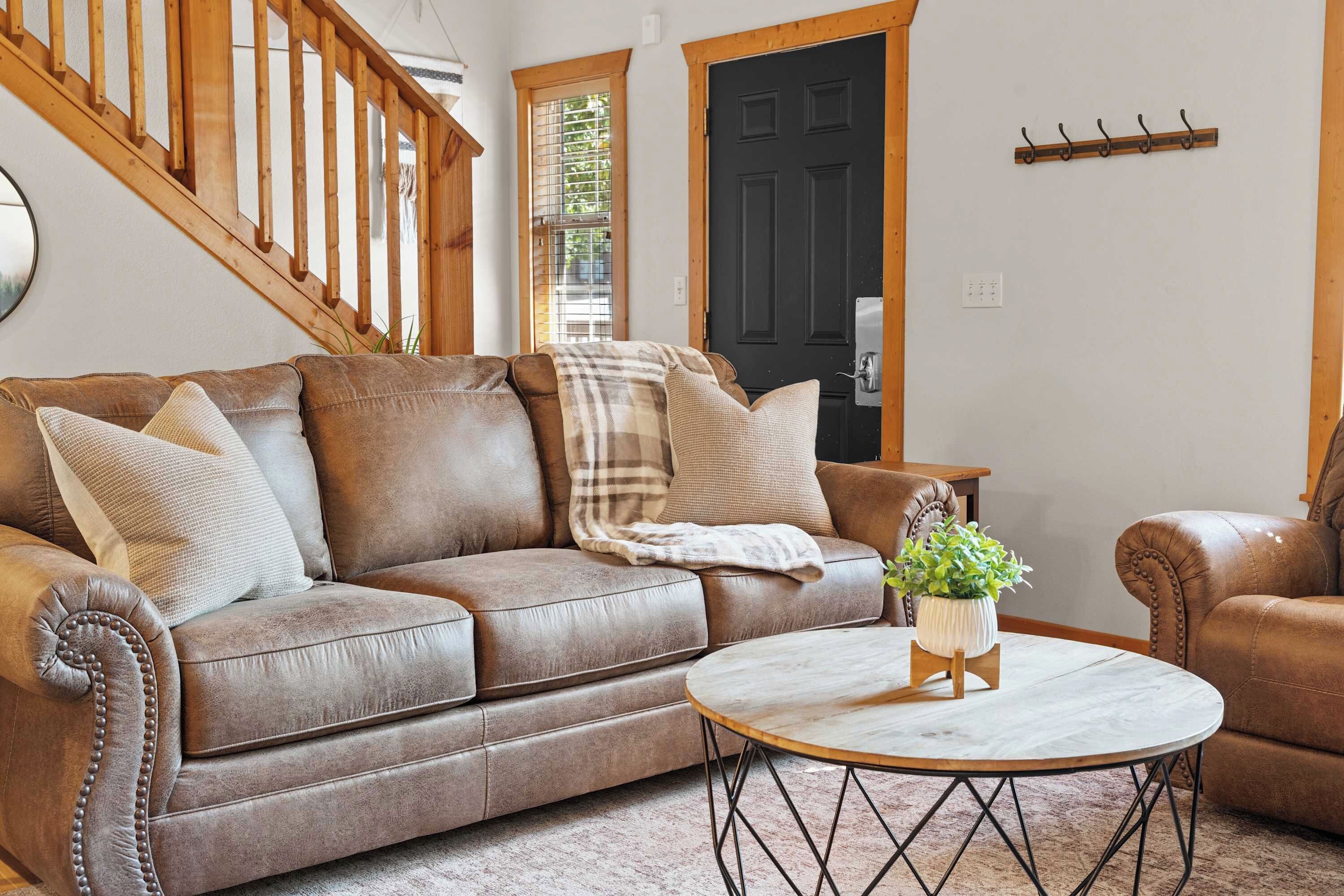 Ein Wohnzimmer mit einem braunen Ledersofa, einem runden Couchtisch und einer Holztreppe.