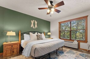 A bedroom with a bed, nightstands, a ceiling fan, a window with blinds, and a wall clock. - Perfect Cabin Retreat! Close to Silver Dollar City (Branson West)