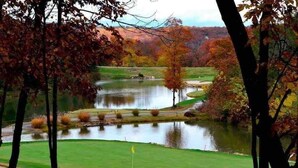 A golf course with a pond, trees, and a flag on the green. - Perfect Cabin Retreat! Close to Silver Dollar City (Branson West)