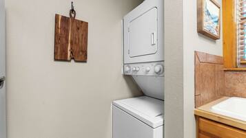 A laundry room with a white washer and dryer, wooden wall-mounted towel racks, and a wooden cabinet with a sink.