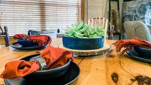 A dining table with plates, bowls, and a centerpiece of green plants. - Cedar Ridge Cabin, Stonebridge Village (Branson West)